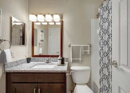 A bathroom with a toilet, sink, mirror, and a shower curtain.