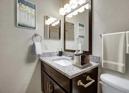 A bathroom with a sink, mirror, and towel rack.