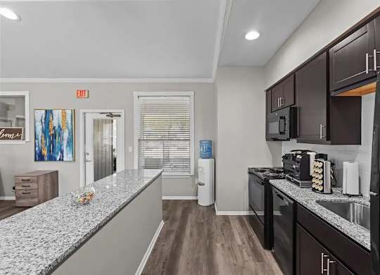 A kitchen with dark brown cabinets and a granite countertop.