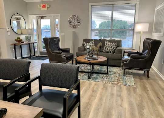 A living room with a grey couch, two chairs and a coffee table.