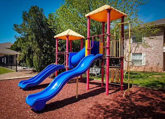 A playground with a blue slide and a yellow canopy.