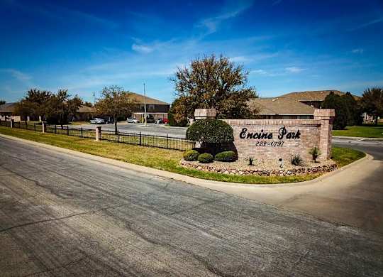 The image shows a sign for Encore Park in front of a building and a street.