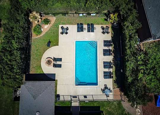 An aerial view of a backyard with a swimming pool and patio furniture.