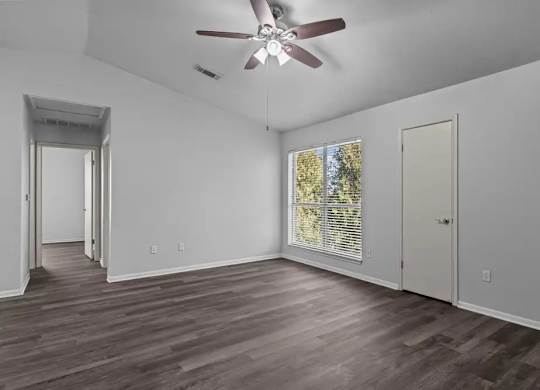 A room with a ceiling fan and wooden flooring.