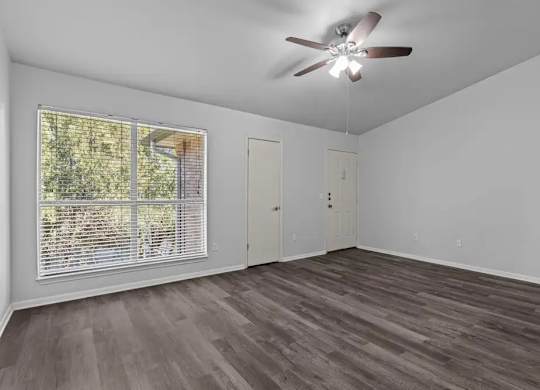 A room with a ceiling fan and a window with blinds.