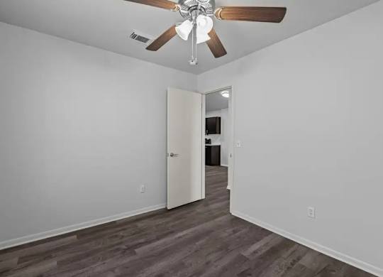 A room with a ceiling fan and a doorway leading to another room.