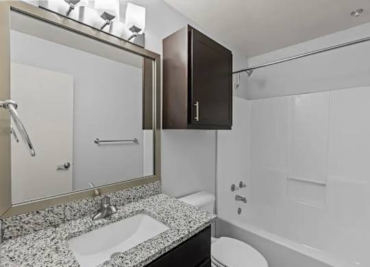 A bathroom with a sink, mirror, toilet and bathtub.