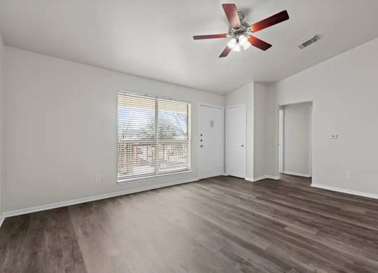 A room with a ceiling fan and a window with blinds.