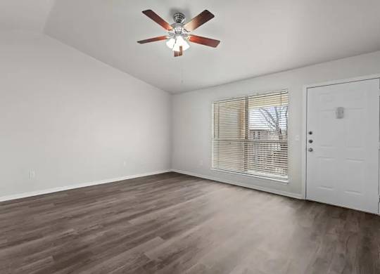 A room with a ceiling fan and wooden flooring.