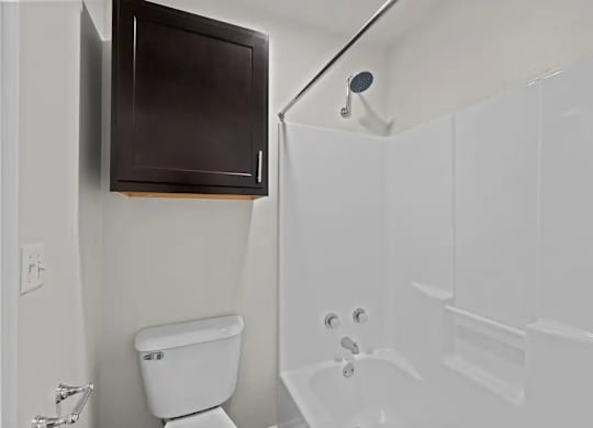 A white toilet sits next to a white bathtub in a bathroom.