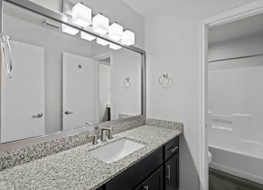 A bathroom with a sink, mirror, and a shower.