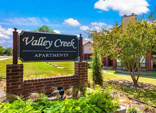 A sign for Valley Creek Apartments is shown in front of a building.