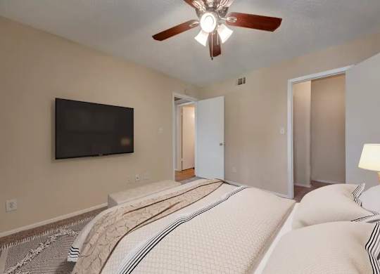 A bedroom with a large bed and a flat screen TV mounted on the wall.