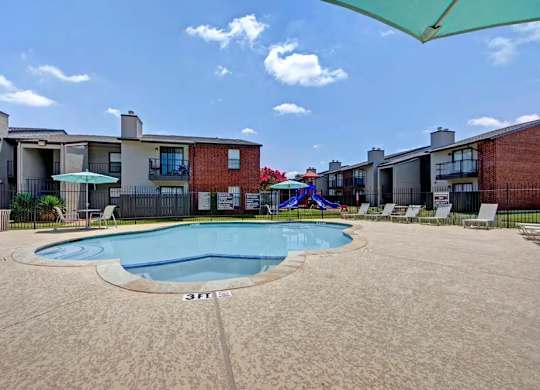 Swimming pool with surrounding patio and lounge chairs at South Meadows Apartments, Texas