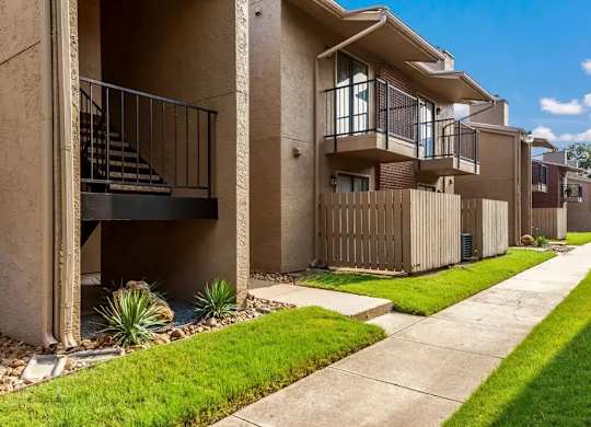 Two story apartment exterior with balconies and patio fencing at South Meadows Apartments, Red Oak, TX