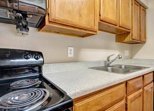 Kitchen with electric stove and double sink at South Meadows Apartments, Red Oak