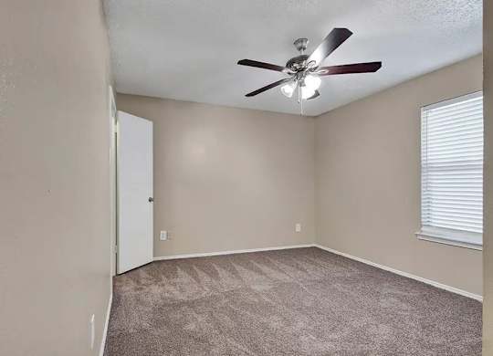 Empty bedroom with carpet and ceiling fan at South Meadows Apartments, Texas, 75154