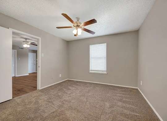 Carpeted bedroom with window and ceiling fan at South Meadows Apartments, Texas