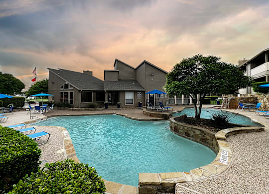 Swimming pool with clubhouse and lounge chairs at Ashwood Park Apartments, Dallas, TX 75252