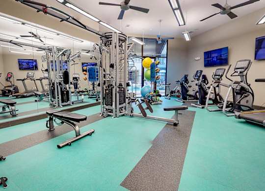 Gym with a variety of equipment including treadmills, weights, and exercise machines at Civic at Frisco Square Apartments, Frisco, Texas