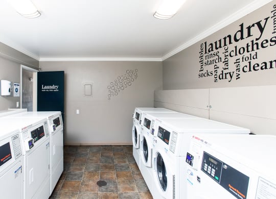 laundry room with four washing machines and a sign on the wall