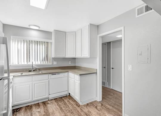 A kitchen with white cabinets and a refrigerator.