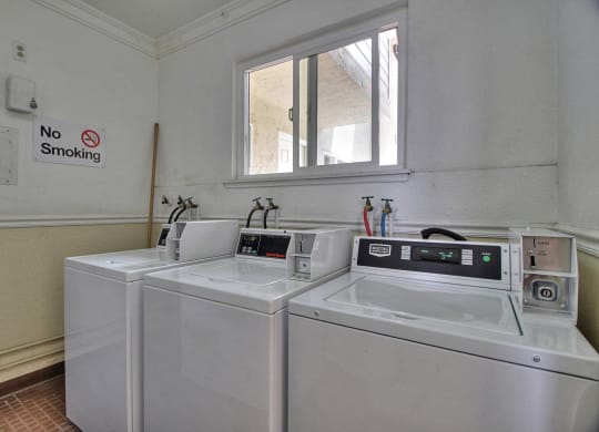 a laundry room with two washing machines and a dryer with a windwo