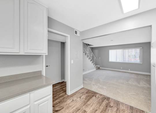 A spacious kitchen with white cabinets and a wooden floor.