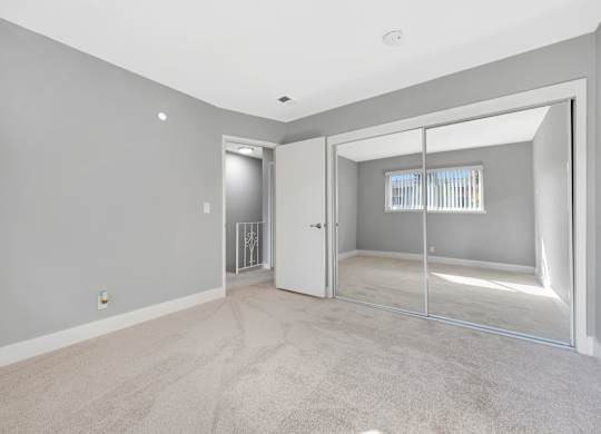 A room with a carpeted floor and a sliding glass door leading to a balcony.