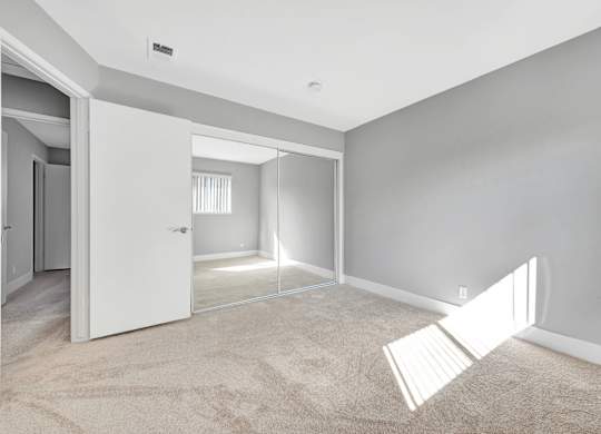 A room with a white door and a carpeted floor.