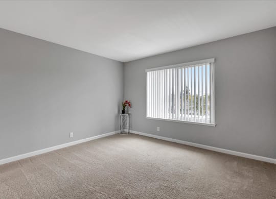 an empty living room with a large window and gray walls