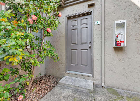 A grey door is closed with a grey mat in front of it.