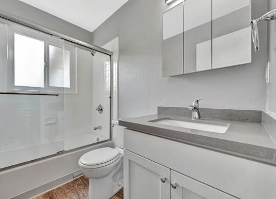 A white bathroom with a toilet, sink, and shower.