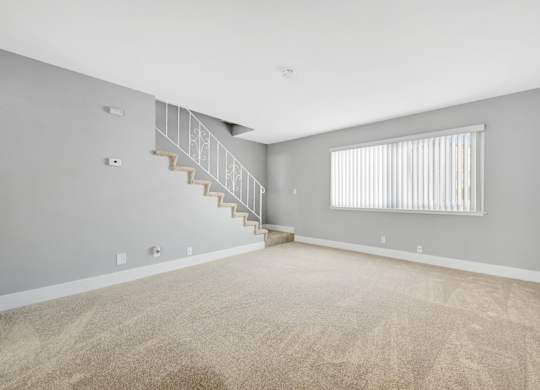 A room with a staircase and a window with blinds.