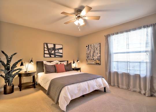 Spacious bedroom with ceiling fan and large window at Rosemeade Apartments, Roseville, California