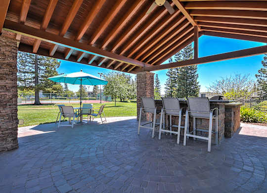 Outdoor patio bar with stone columns and seating at Rosemeade Apartments, Roseville, California