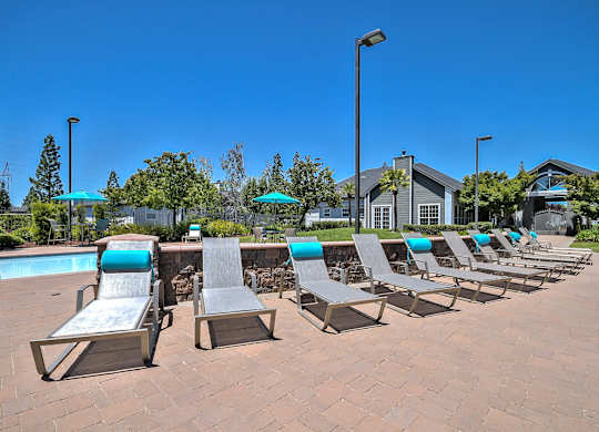 Pool deck with lounge chairs and turquoise accents at Rosemeade Apartments, Roseville, California