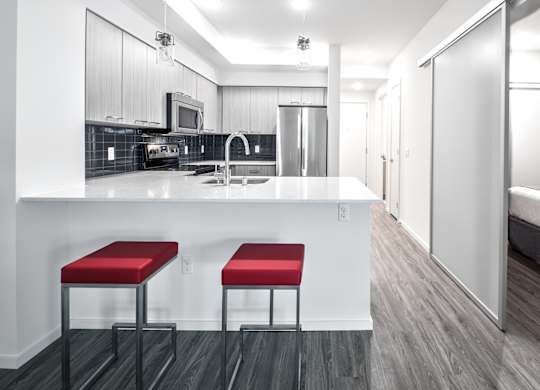 A kitchen with a white counter and red stools.