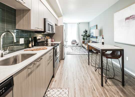 A modern kitchen with a dining area in the background.