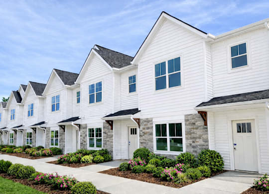 white houses with green bushes in front at Ventura Townhouses, West Olive
