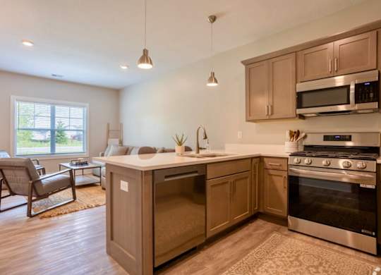 A kitchen with wooden cabinets and stainless steel appliances at Ventura Townhouses, West Olive  , Michigan