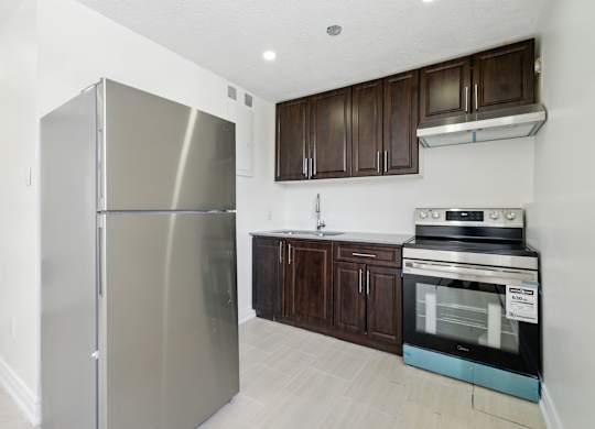 A modern kitchen with a stainless steel refrigerator and dark brown cabinets.