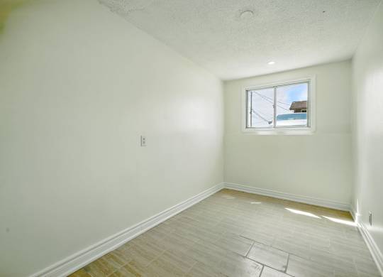 A room with a window and wooden flooring.