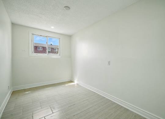 A room with a window and wooden flooring.