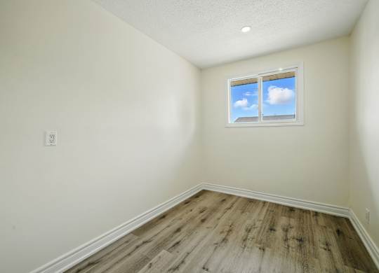 A room with a window showing a blue sky with clouds.