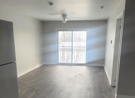 A room with a grey floor and a window with blinds.