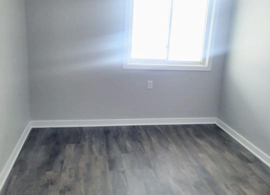 A room with a window and wooden flooring.