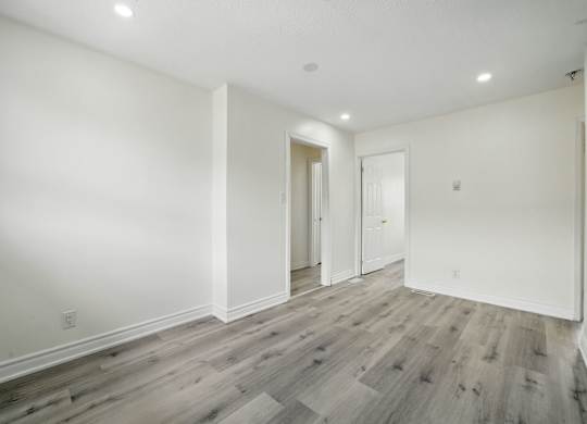 A room with wooden flooring and white walls.