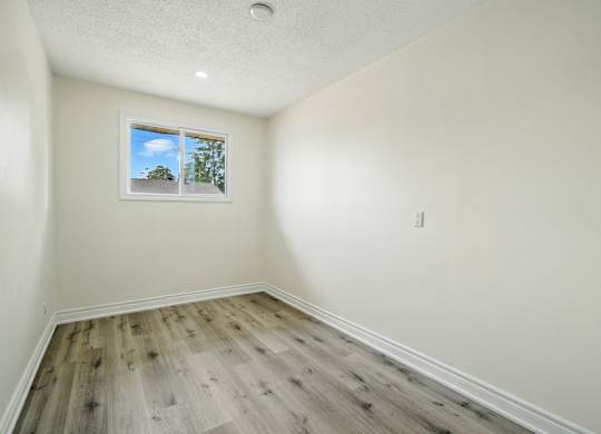 A room with a window and wooden flooring.