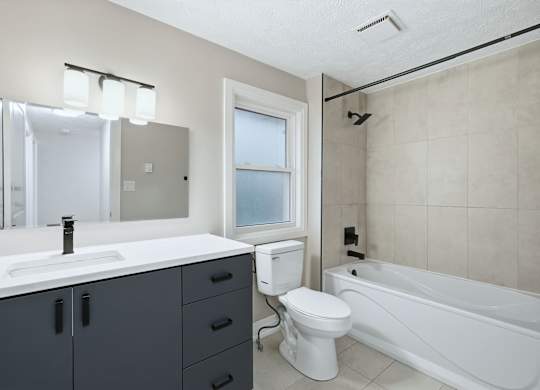 A white toilet sits next to a white sink in a bathroom.